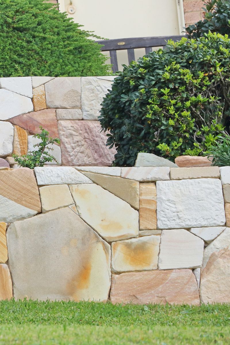 Image of a sandstone retaining wall with some shrubs